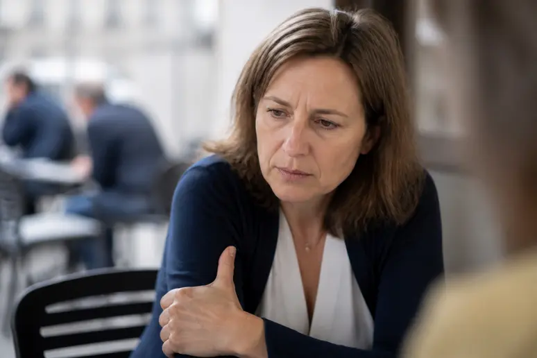 Femme française inquiète touchant son bras gauche, symptôme potentiel de douleur bras gauche stress.