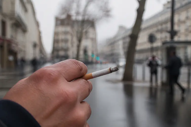 Main tenant une cigarette, symbolisant un facteur de risque de maladie cardiaque, lien avec douleur bras gauche stress.